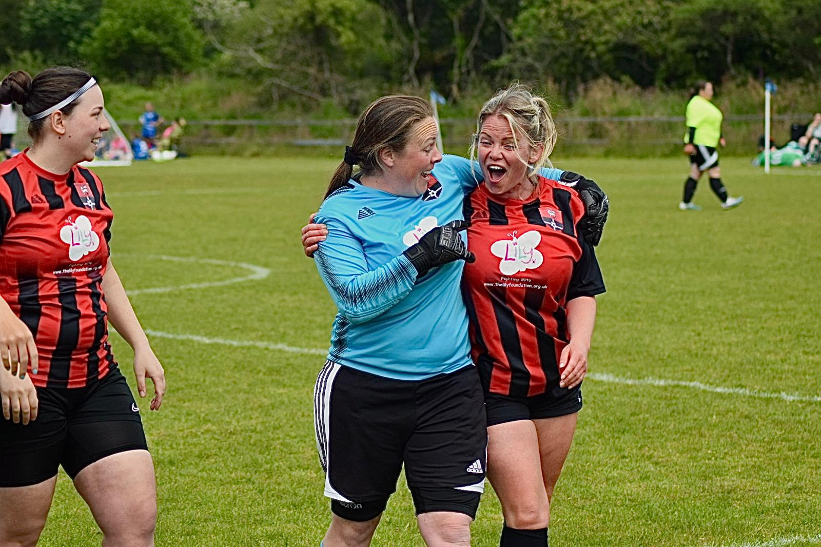 Redruth United women's players celebrating with the goalkeeper, Lily Foundation logo on their shirts