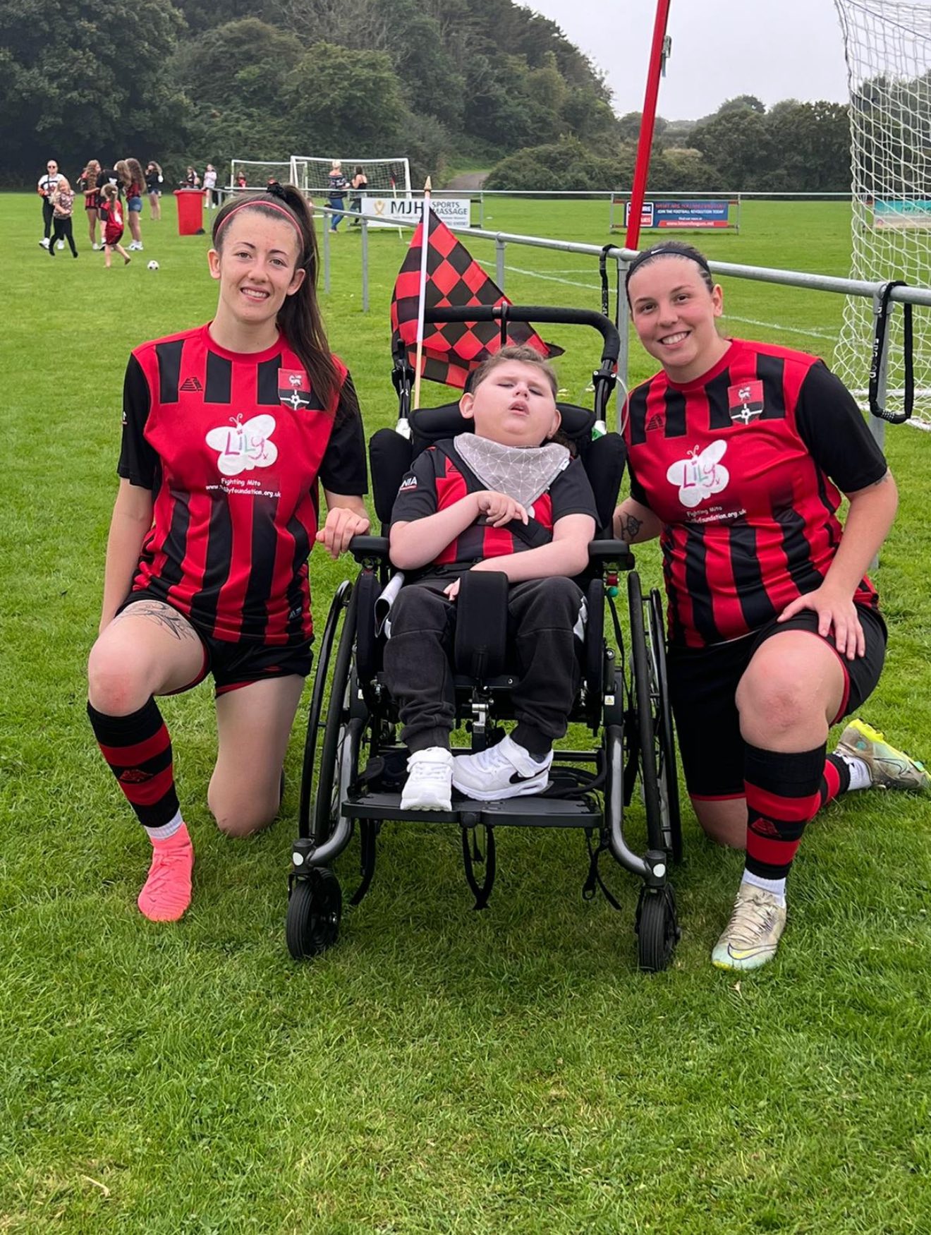 Jude alongside Redruth United women's players on the pitch at Clijah Park